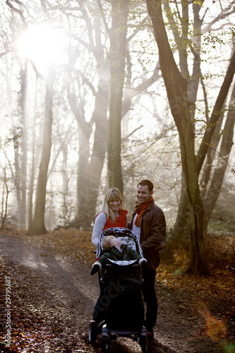 Photo: A young couple pushing a stroller in the park, talking A young couple pushing a stroller in the park, talking