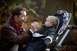 A young father feeding his son in the park