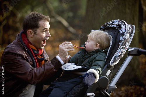 Photo: A young father feeding his son in the park A young father feeding his son in the park