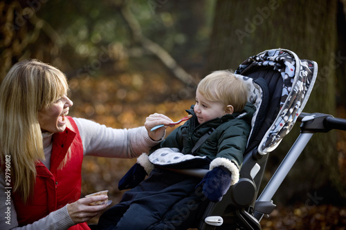 Photo: A young mother feeding her son in the park A young mother feeding her son in the park