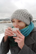 The young white frozen girl drinks hot tea in the winter