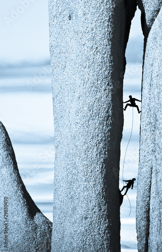 Photo: Team of climbers struggel up a steep cliff. Team of climbers struggel up a steep cliff.