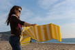 Young woman laying down a beach mat on the sand