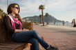 Happy young woman smiling on a beach bench