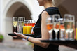 Waiter with dish of champagne, wine and juice glasses