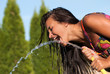 The young girl drinking water from a hose
