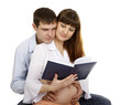 pregnant woman and her husband reading a book