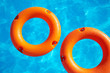 two orange life buoy  on water