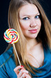 Beautiful girl holding a candy on a stick in his hand