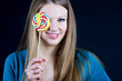 Beautiful girl holding a candy on a stick in his hand