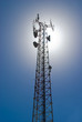 Cell tower and radio antenna back lit by sun