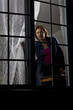 Woman looking out from behind a window