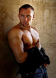 A muscular young man standing by the wall