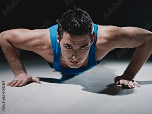 Photo: Man doing push-ups on black background Man doing push-ups on black background