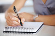 Woman's hand holding a pen taking notes