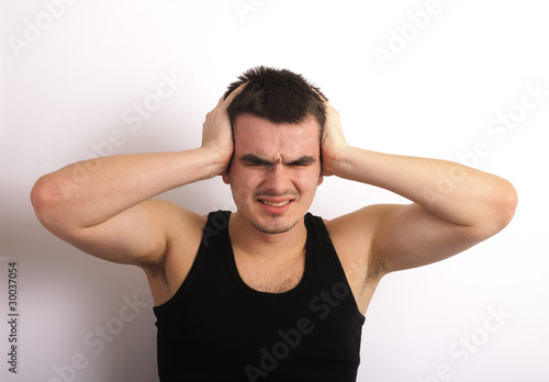 Photo: Stressed young man covering his ears Stressed young man covering his ears