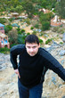 Climbing boy on rock in front of bright colorful scenery