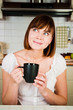 young  woman, enjoying a cup of coffee in her home.