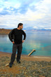 Man standing on mountain in front of blue sea and sky
