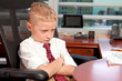 Cute young boy in a business office with mad expression