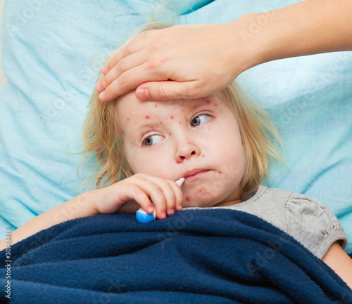 Photo: a mother measures the temperature of her sick daughter a mother measures the temperature of her sick daughter
