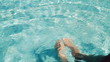 Man's feet splashing water in swimming pool