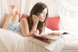 Foto: Junges Mädchen liegt mit Zeitschrift im Bett Junges Mädchen liegt mit Zeitschrift im Bett
