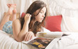Foto: Junges Mädchen liegt mit Zeitschrift im Bett Junges Mädchen liegt mit Zeitschrift im Bett