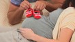 Future parents holding little red shoes