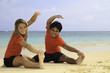 young couple doing yoga, exercise, and stretches on a beach young couple doing yoga, exercise, and stretches on a beach
