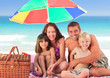Family picnicking under a sol umbrella on the beach