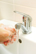 hands covered with soap being washed in the sink