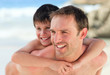 Father having son a piggyback on the beach