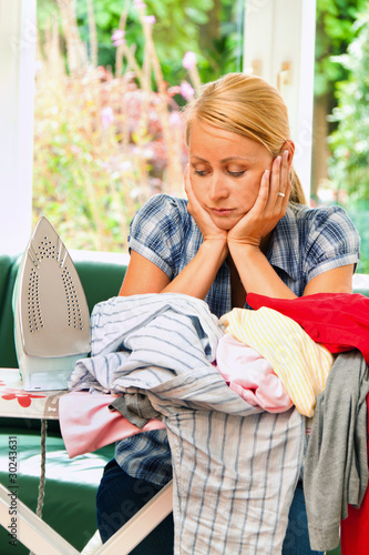 Foto: Hausfrau beim Bügeln mit Bügeleisen und Wäsche. Hausfrau beim Bügeln mit Bügeleisen und Wäsche.
