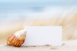 Shells and a blank card on the beach for a message