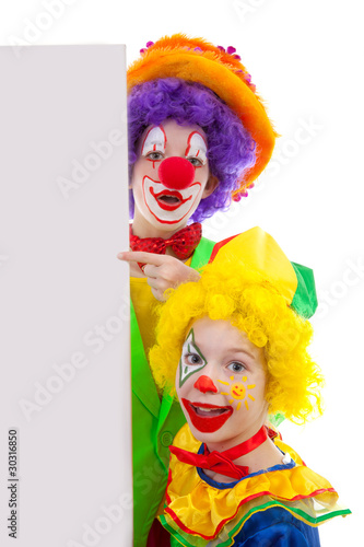 Photo: Two girl clowns holding empty text board over white background Two girl clowns holding empty text board over white background