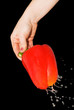 red pepper in a female hand with a spray of water