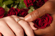 Newly engaged couple showing off ring with red roses