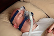 Man with sleep apnea using a CPAP machine in bed. Man with sleep apnea using a CPAP machine in bed.