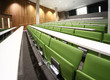 large auditorium with rows of green seats and white tables large auditorium with rows of green seats and white tables