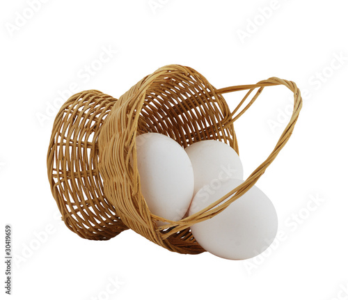Photo: three white eggs spilled from straw interwoven basket three white eggs spilled from straw interwoven basket