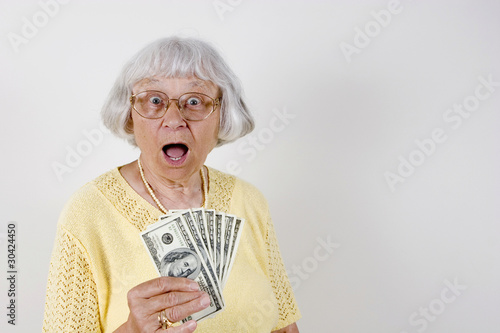 Photo: Shocked senior woman holding lots of cash Shocked senior woman holding lots of cash