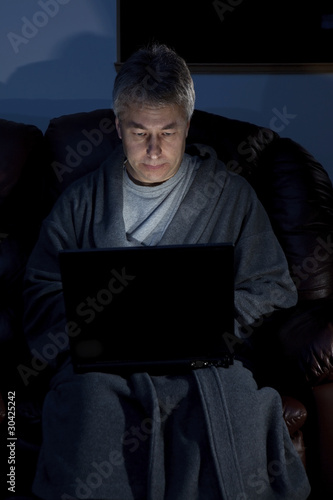 Photo: Man in housecoat working late series serious Man in housecoat working late series serious