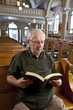 Foto: Senior man reading a bible in church Senior man reading a bible in church