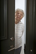 Photo: Annoyed senior woman answering front door Annoyed senior woman answering front door
