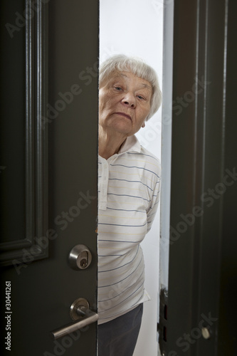 Photo: Annoyed senior woman answering front door Annoyed senior woman answering front door