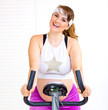 Photo: Happy pregnant woman working out on static bike at home. Happy pregnant woman working out on static bike at home.