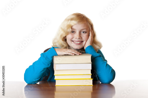 Foto: Junges Schulmädchen sitzt glücklich mit Büchern am Schreibtisch Junges Schulmädchen sitzt glücklich mit Büchern am Schreibtisch