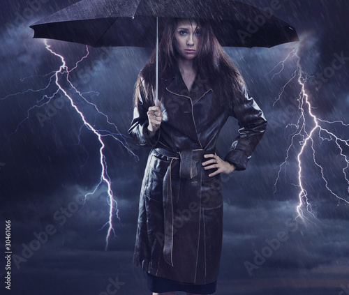 Photo: Single woman wearing coat holding umbrella. Creative szmbol of t Single woman wearing coat holding umbrella. Creative szmbol of t