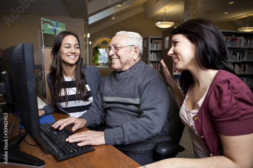 Photo: Volunteers teaching a senior how to use a computer Volunteers teaching a senior how to use a computer